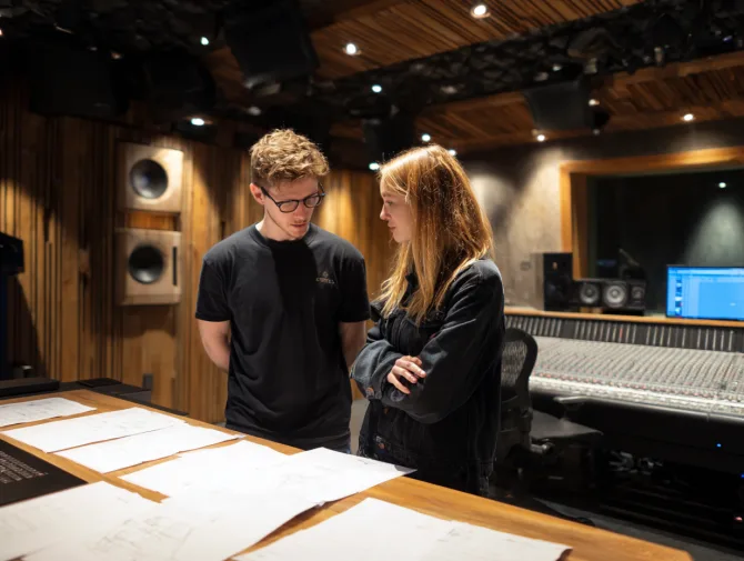 Client and engineer reviewing plans at a mixing console in a recording studio